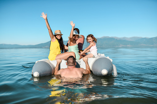 Fun Times For Happy Family Having Boat Ride On Lake During Vacation