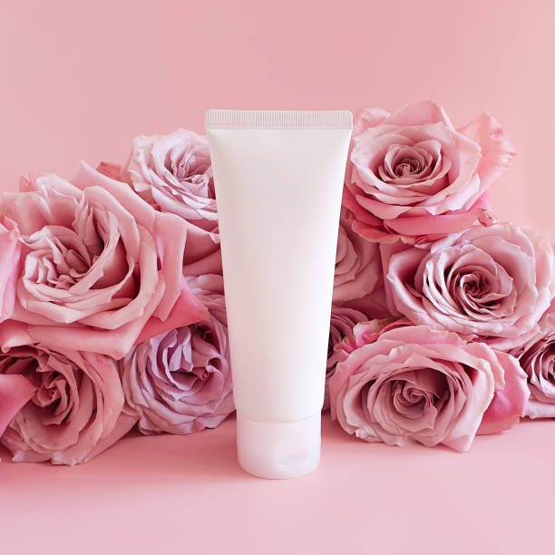 Mockup of white squeeze bottle plastic tube for branding of medicine or cosmetics - cream, gel, skincare, toothpaste and pink roses flowers a lot on pink background. Bio organic beauty blank, front maqueta de tubo de plástico de botella de compresión blanca para la marca de medicamentos o cosméticos: crema, gel, cuidado de la piel, pasta de dientes y flores de rosas rosas mucho sobre fondo rosa. belleza bio orgánica en blanco, frente