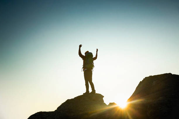 istock Man with arms raised at sunset 1384275828