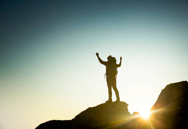 istock Man with arms raised at sunset 1384275833