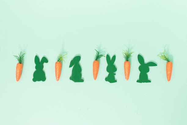 istock Pattern made with carrots and bunnies for Easter season on pastel green colored background with copy space. Minimal Easter Holiday concept for greeting card or banner template. 1384276476