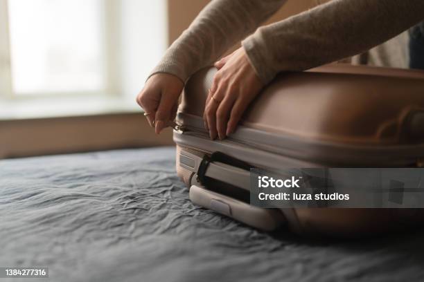 Woman Packing A Suitcase For A Trip Stock Photo - Download Image Now - Suitcase, Closing, Closed