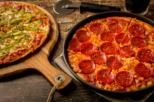 istock Green pepper pizza and Pepperoni pizza on wood table 1384278692