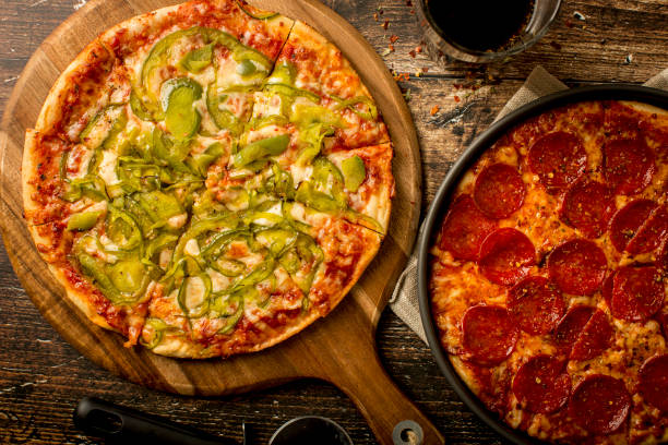 istock Green pepper pizza and Pepperoni pizza on wood table 1384278893