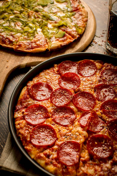 istock Green pepper pizza and Pepperoni pizza on wood table 1384278896