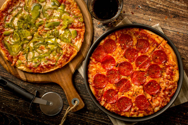 pizza al peperone verde e pizza ai peperoni sul tavolo di legno - tomato sauce domestic kitchen meat cheese foto e immagini stock