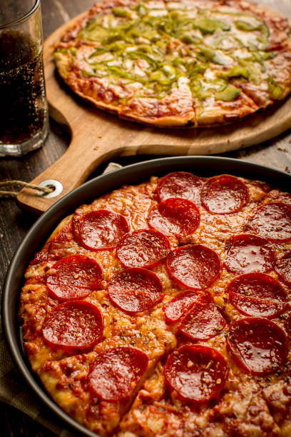 istock Green pepper pizza and Pepperoni pizza on wood table 1384279061
