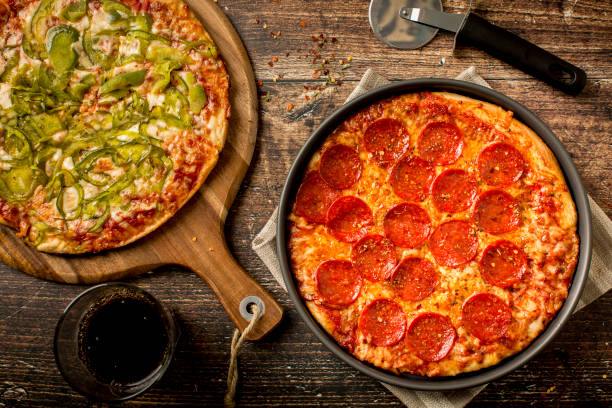 istock Green pepper pizza and Pepperoni pizza on wood table 1384279121