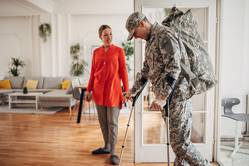 Military soldier with crutches coming back home to his wife from the war