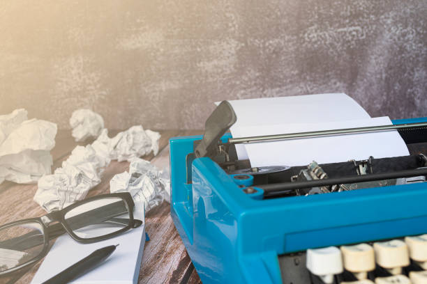 istock An old blue typewriter and trash paper on wooden desk. Copy space 1384284698