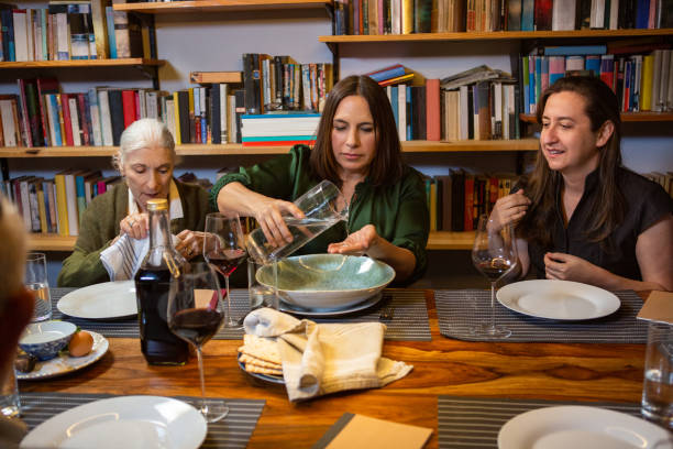 Women Washing Hands at Passover Seder A modern Jewish American family celebrates Passover together. They are gathered around the dining table, passing a pitcher of water and a bowl for hand washing. passover celebration stock pictures, royalty-free photos & images