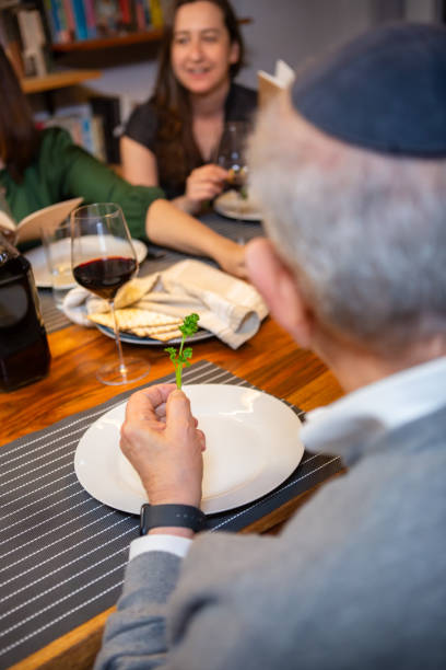 petersilie in salzwasser tauchen beim pessach-seder - seder passover judaism family stock-fotos und bilder