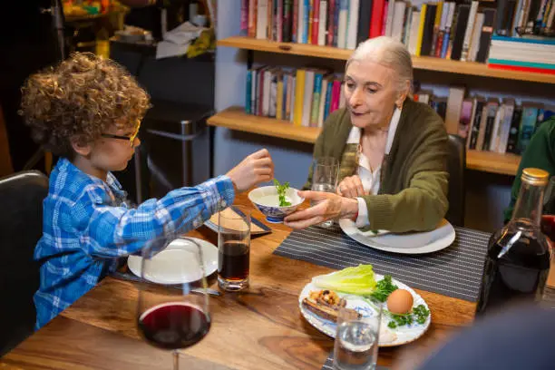 A modern Jewish American family celebrates Passover together, dipping the karpas (parsley) in salt water as a reminder of the tears of the enslaved Israelites.