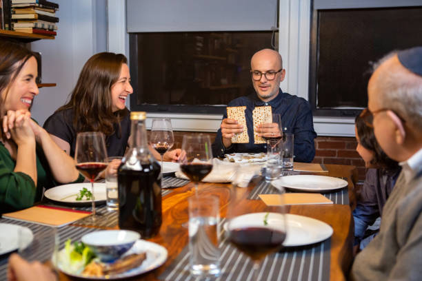 Breaking Matzo at Family Passover Seder A modern Jewish American family celebrates Passover together.  The Seder leader breaks the middle matzo (Yachatz). matzo stock pictures, royalty-free photos & images