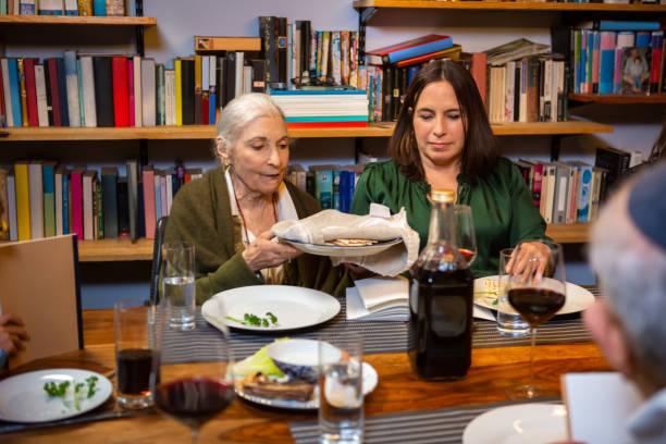 une femme prend matzo de l’assiette au seder de la famille - seder passover judaism family photos et images de collection