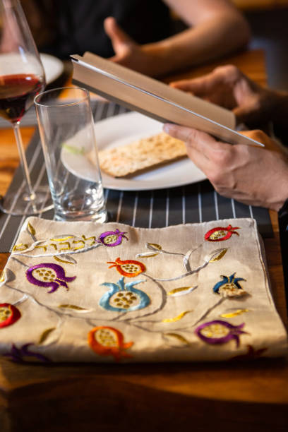 Wrapped Afikomen and Haggadah at Passover Seder A piece of matzo wrapped in an embroidered cloth on the table during a family Passover seder. The afikomen is hidden for the children to hunt for it. afikomen stock pictures, royalty-free photos & images