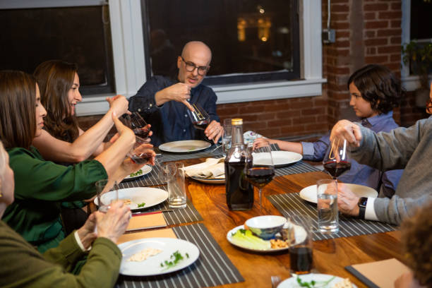 Enumeration of Ten Plagues at Passover Seder A modern Jewish American family celebrates Passover together. The seder leader is reciting the ten plagues of Egypt, which the others repeat while spilling drops of wine. passover celebration stock pictures, royalty-free photos & images