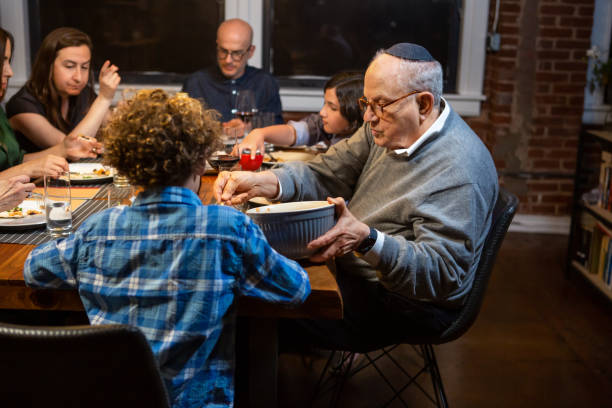 Making Hillel Sandwich at Passover Seder A modern Jewish American family celebrates Passover together, making a "Hillel sandwich" by combining charoset (a sweet mixture of fruit) and maror (bitter herbs) between two pieces of matzo. passover celebration stock pictures, royalty-free photos & images