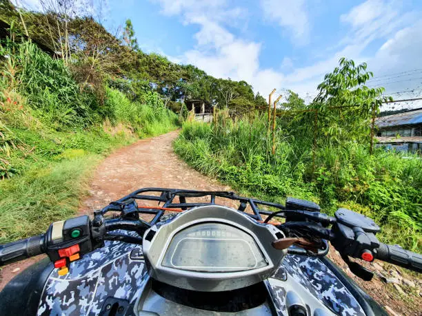 First person view in the middle of the jungle, ATV driver in the mud. Adventure trip in the forest. Soft focus. Man on quadbike race over rough terrain in the forest on a hot summer day