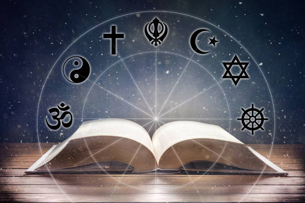 Book on wooden table with religious symbology and universe background stock photo