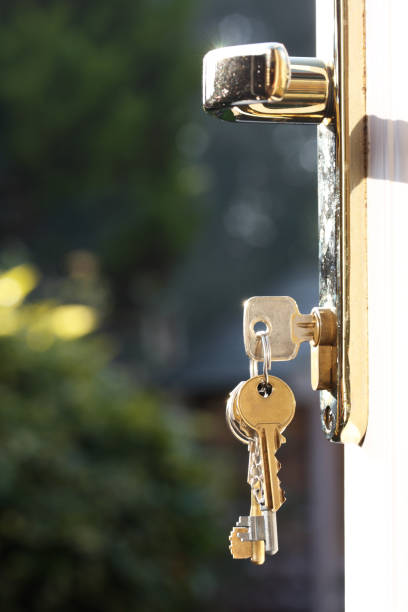 House keys in lock of a door viewed outside vertical stock photo