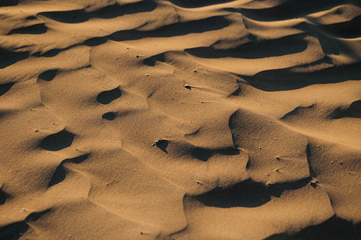 close up high angle view of beautiful sandy beach dunes lit by the sunlight with projected shadows