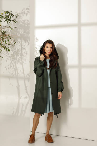 istock Female model wearing trendy spring outfit, khaki raincoat against white background. Spring, summer fashion concept 1384311683