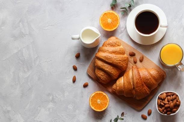 Croissants with orange juice, orange fruit, coffee with milk and almond nuts on the table. French or continental breakfast. Selective focus, top view and copy space Croissants with orange juice, orange fruit, coffee with milk and almond nuts on the table. French or continental breakfast. Selective focus, top view and copy space. continental breakfast stock pictures, royalty-free photos & images