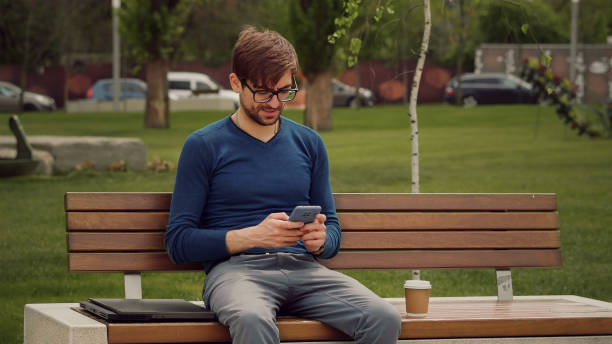 istock Portrait focused man writing using mobile phone outdoor. 1384312896