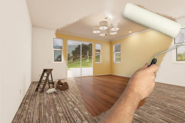 before and after of man painting roller to reveal newly remodeled room with light yellow paint and new floors. - house painter paint roller yellow painting imagens e fotografias de stock