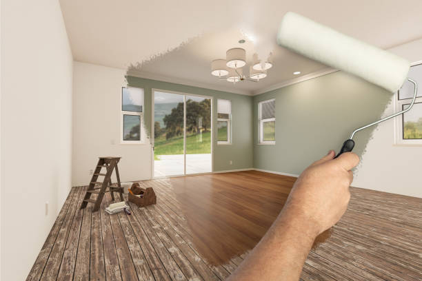 男の塗装ローラーの前後に新鮮なライトグリーンの塗料と新しい床で新しく改装された部屋を明らかにします。 - 住宅リフォーム ストックフォトと画像