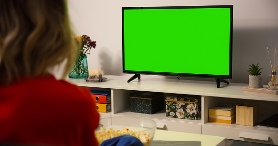 Green Screen TV Close up. Shot behind model Shoulder watching Tv sitting on the couch.