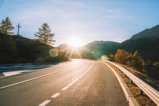 low angle view on simplon pass road in swiss alps in the warm light of the sunset backlit