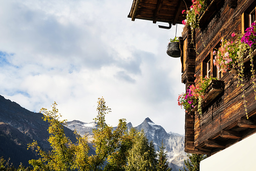 typical wooden facade with flower boxes in the swiss valais canton in the Binntal area with mountains in the background