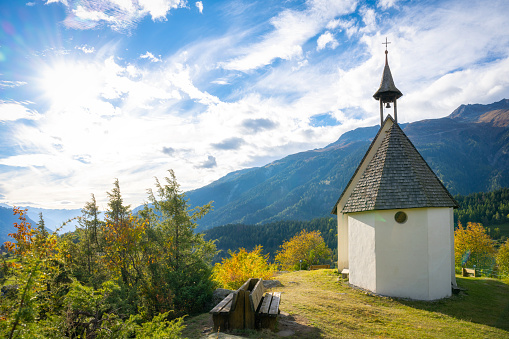 view on little chapel historic village Mühlebach in green sunny valley with the mountains of the swiss alps in the background