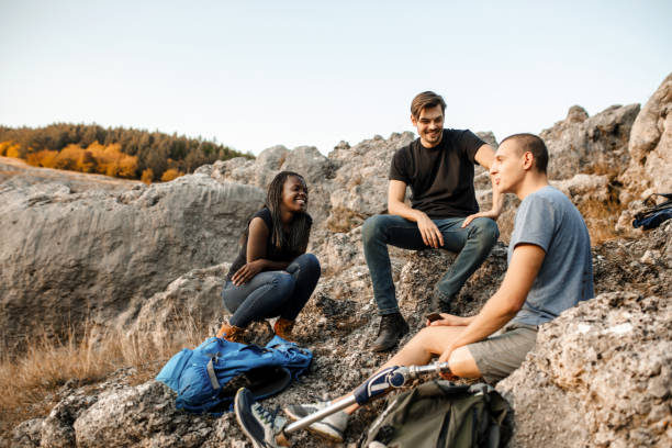 istock Disabled young man with artificial leg is resting with friends on a hike 1384328648