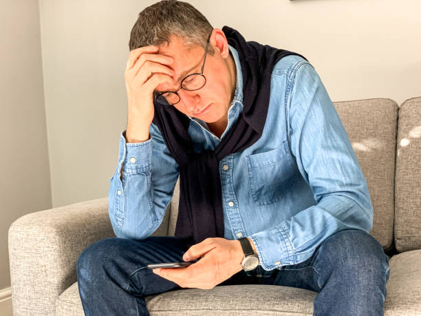 istock Middle aged man sitting on sofa at home in the morning before going to office and checking news 1384330160