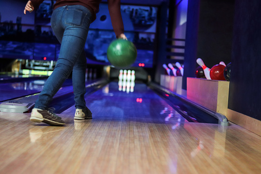 Woman in club for bowling is throwing ball