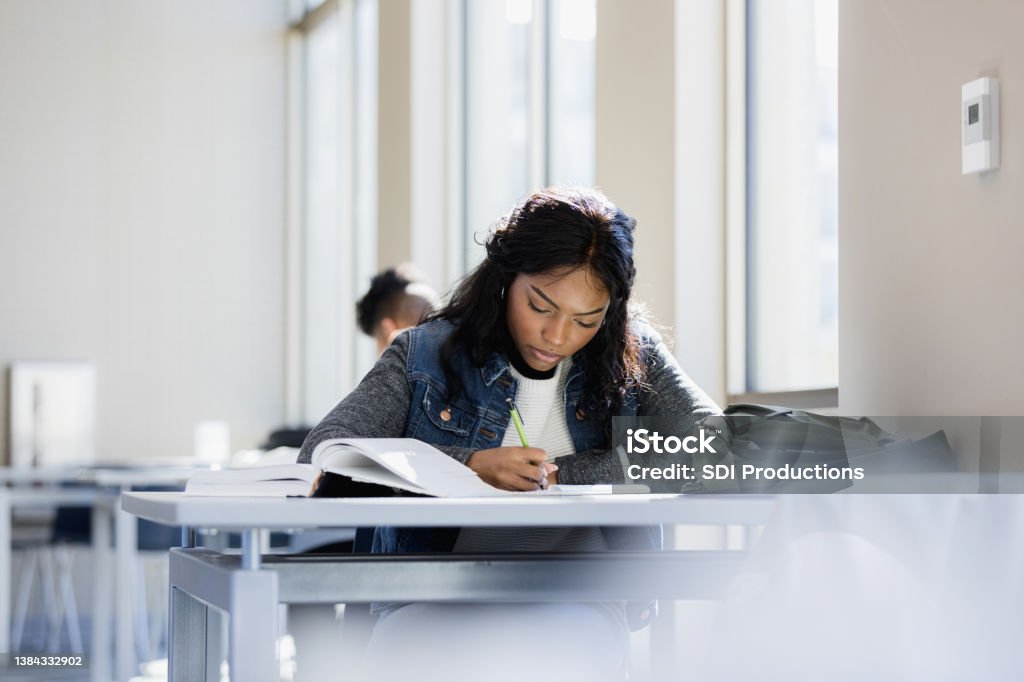 Focused young woman The young woman is focused on reading through her textbook. University Student Stock Photo