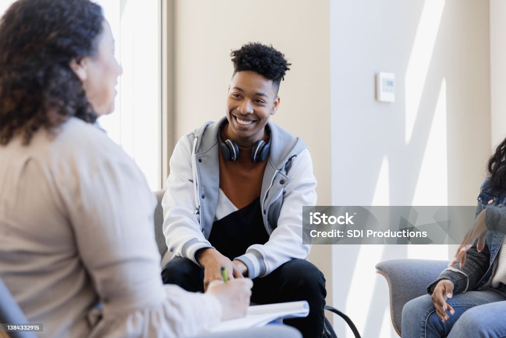 Smiling young adult The young adult is smiling while listening to his mentor encourage him. Psychotherapy Stock Photo