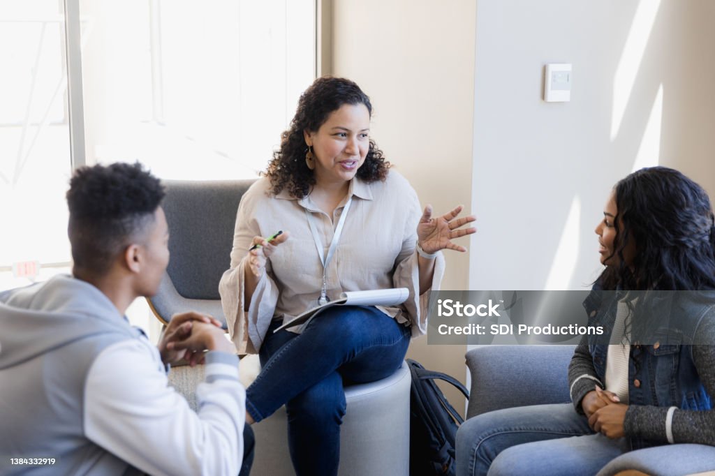 Professor has small group meeting The professor has a small group meeting with the students to help them with their project. Mental Health Professional Stock Photo