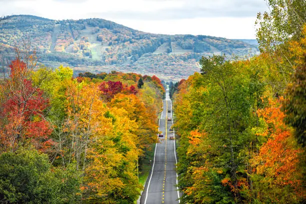 Photo of West Virginia road highway with many cars traffic in colorful autumn fall near Blackwater Falls State park and Seneca Rocks with steep ski resort slope hill