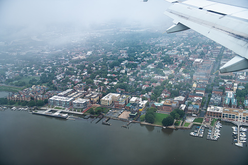 Airplane aerial view through window of Alexandria in Northern Virginia on a cloudy day near Washington DC Potomac river descending to Reagan National Airport