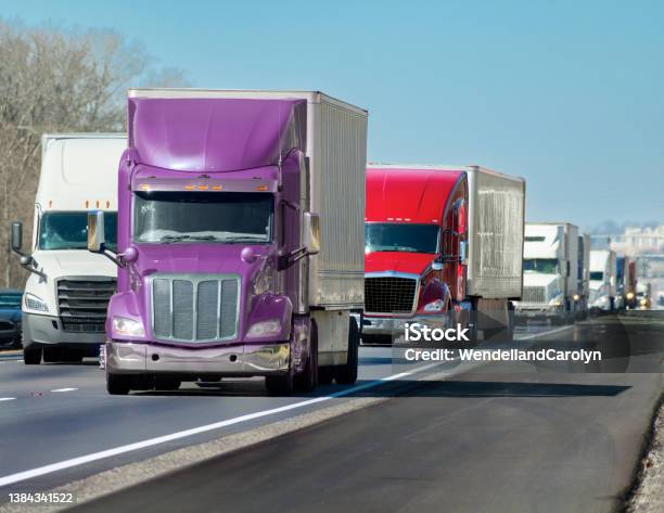 Multicolored Convoy Of Big Trucks Rolls Down The Interstate Stock Photo - Download Image Now