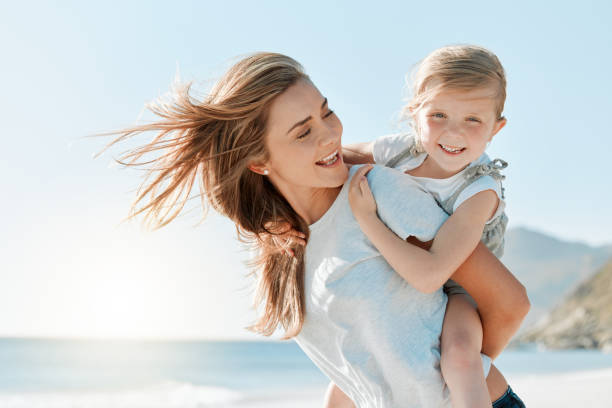 istock Shot of a woman carrying her daughter on her back while at the beach 1384341663