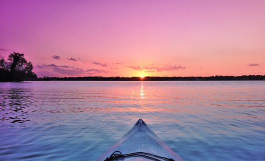 Kayaking towards the treelined horizon thru aqua turquoise water under pink skies.