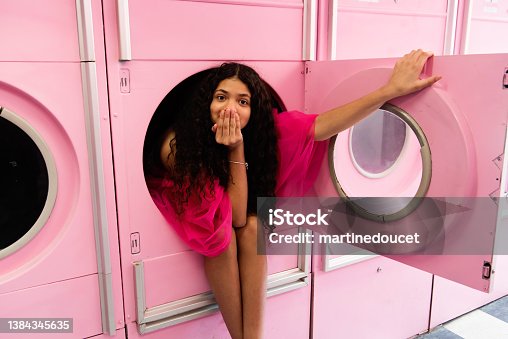 istock Portrait of cute teenage girl in a vintage pink drying machine. 1384345635