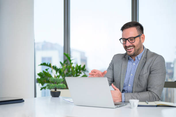 istock Smiling attractive young manager with a stylish short beard talking with his clients online and discussing a business proposal 1384352451