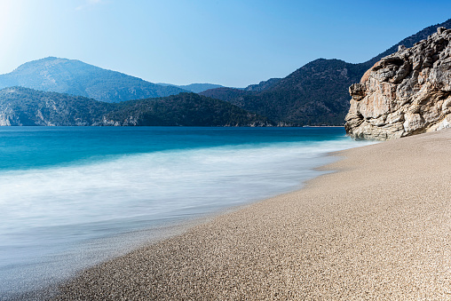 White foamy waves approaching the sand on the shore by the sea in Fethiye, Turkey. Long exposure.