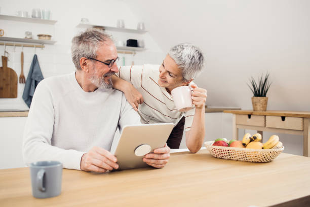 istock Happy senior couple enjoying coffee and using tablet at home 1384369374